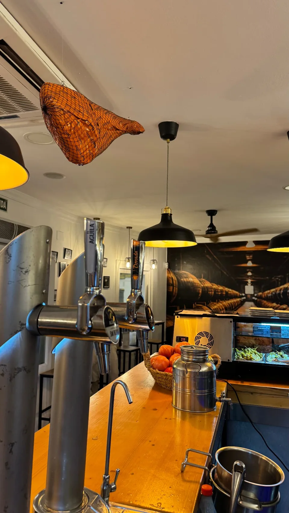 Barra con tiradores de cerveza y jamón colgado