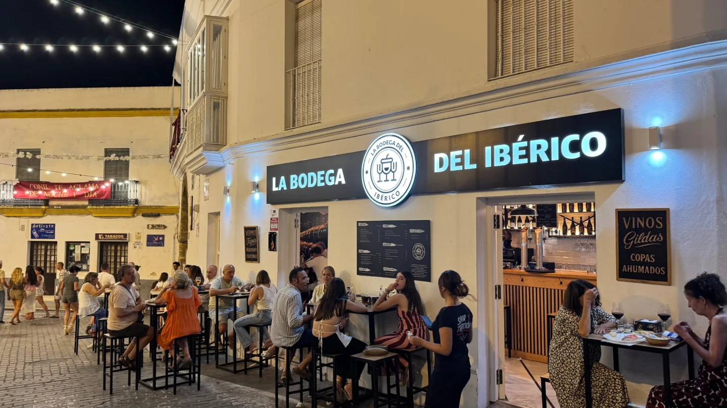 Fachada de La Bodega del Ibérico con terraza llena por la noche