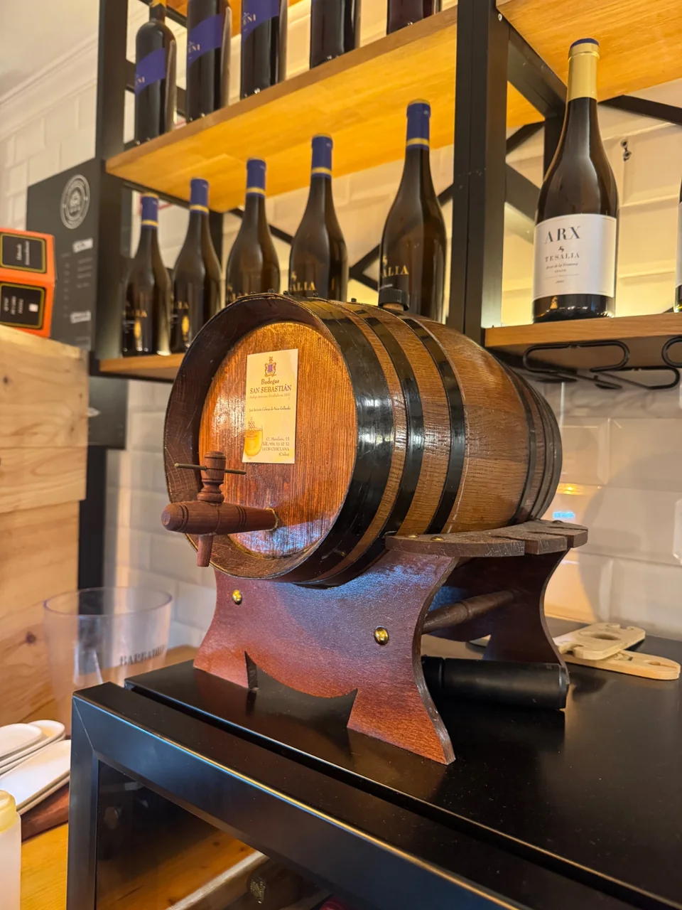 Barrica de vino con botellas de ARX y Tesalia al fondo